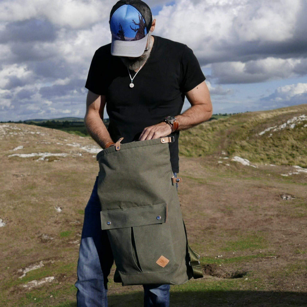 Man searching for camera in his outdoor canvas backpack