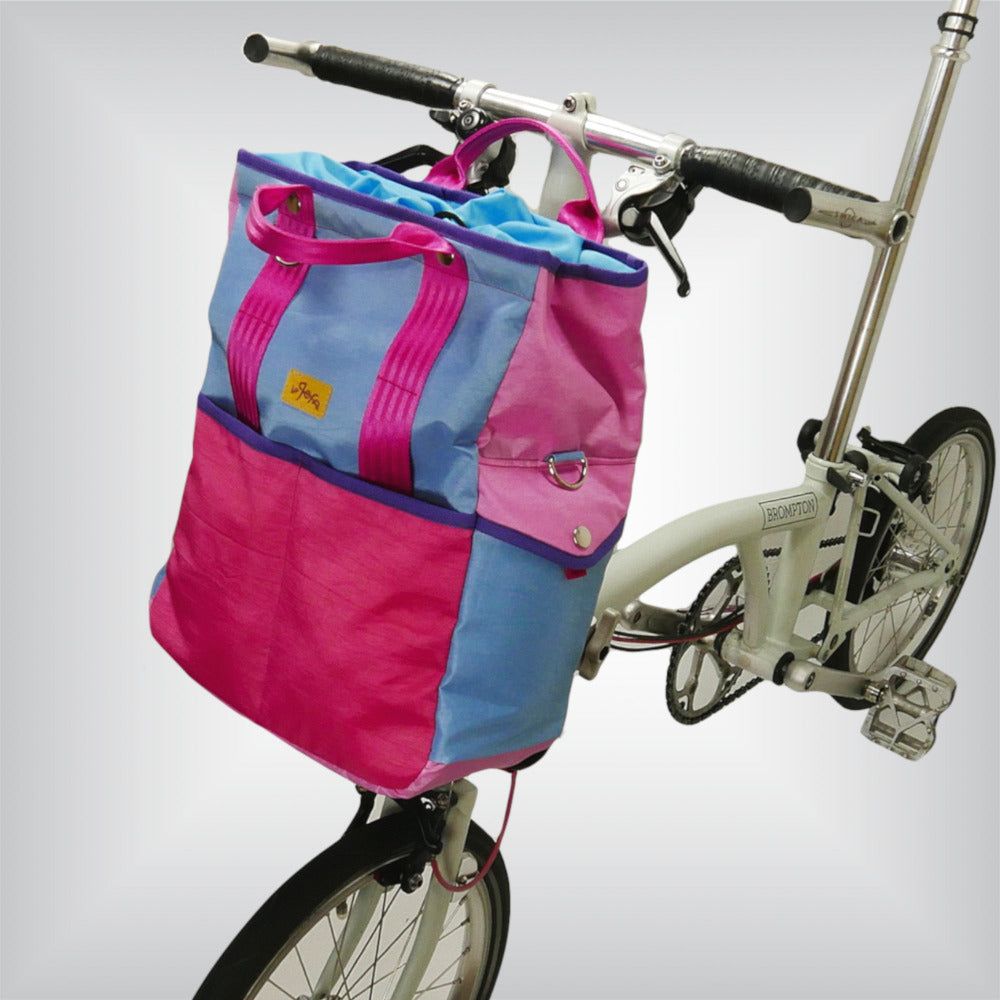 Brompton-ready 'HardCandy' bag, presenting a trendy, pink-toned cycling accessory with 14-18 L capacity, external pockets, and a convenient snap button closure for a secure and stylish commute