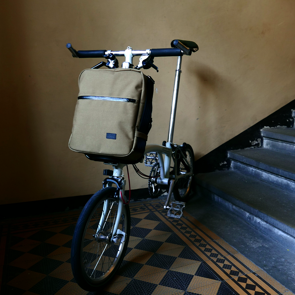  front bag for Brompton bikes, combining retro aesthetics with modern features like a padded netbook sleeve and secure phone slot.